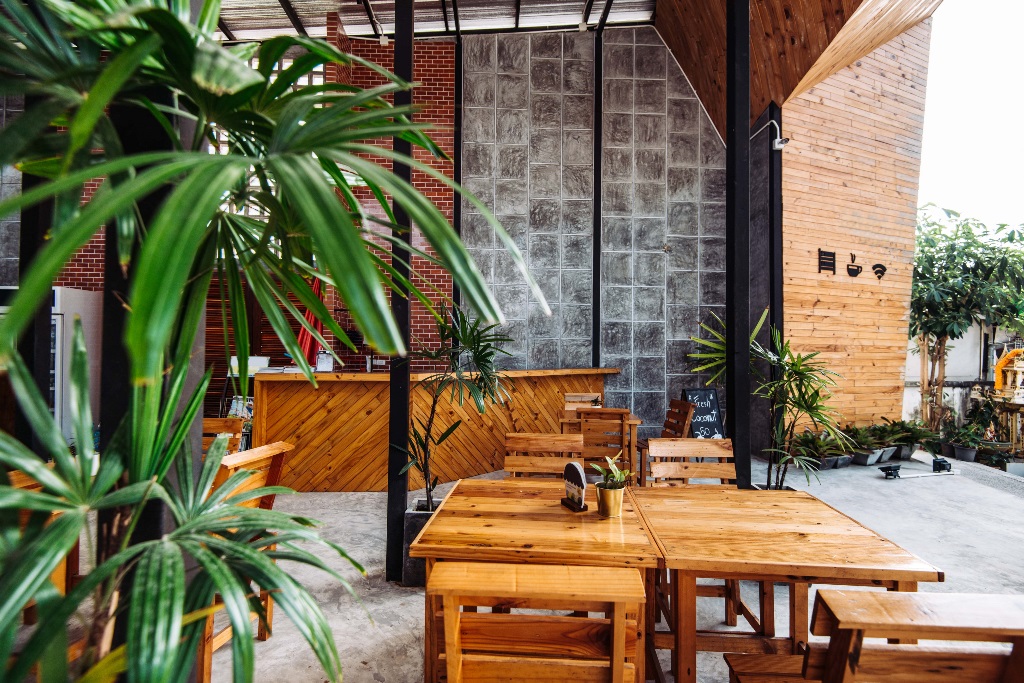 wooden tables and chairs in a room with a plant